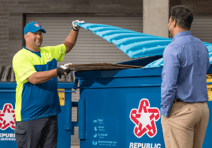 garbage employee helping business owner at dumpster