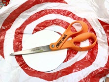 scissors on top of plastic grocery bag and round cardboard circle