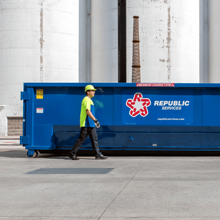 Employee with large roll-off dumpster-