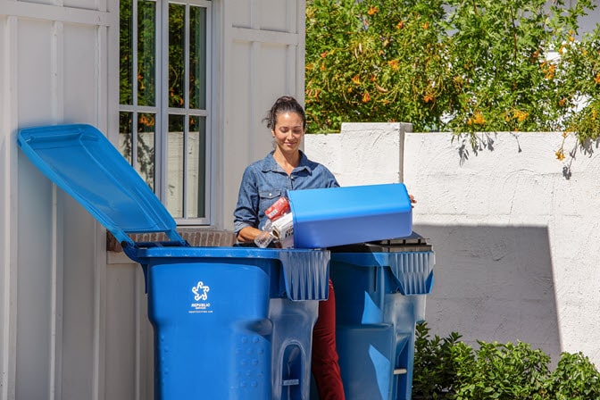 All-in-one-recycling-woman-empties-loose-recyclables-into-outdoor-cart