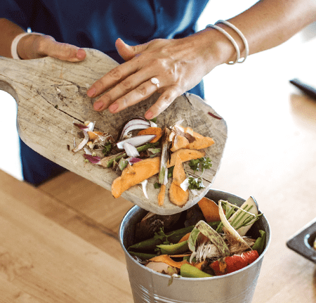 person placing food waste into a countertop bin