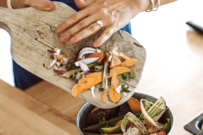 person placing food waste into a countertop bin